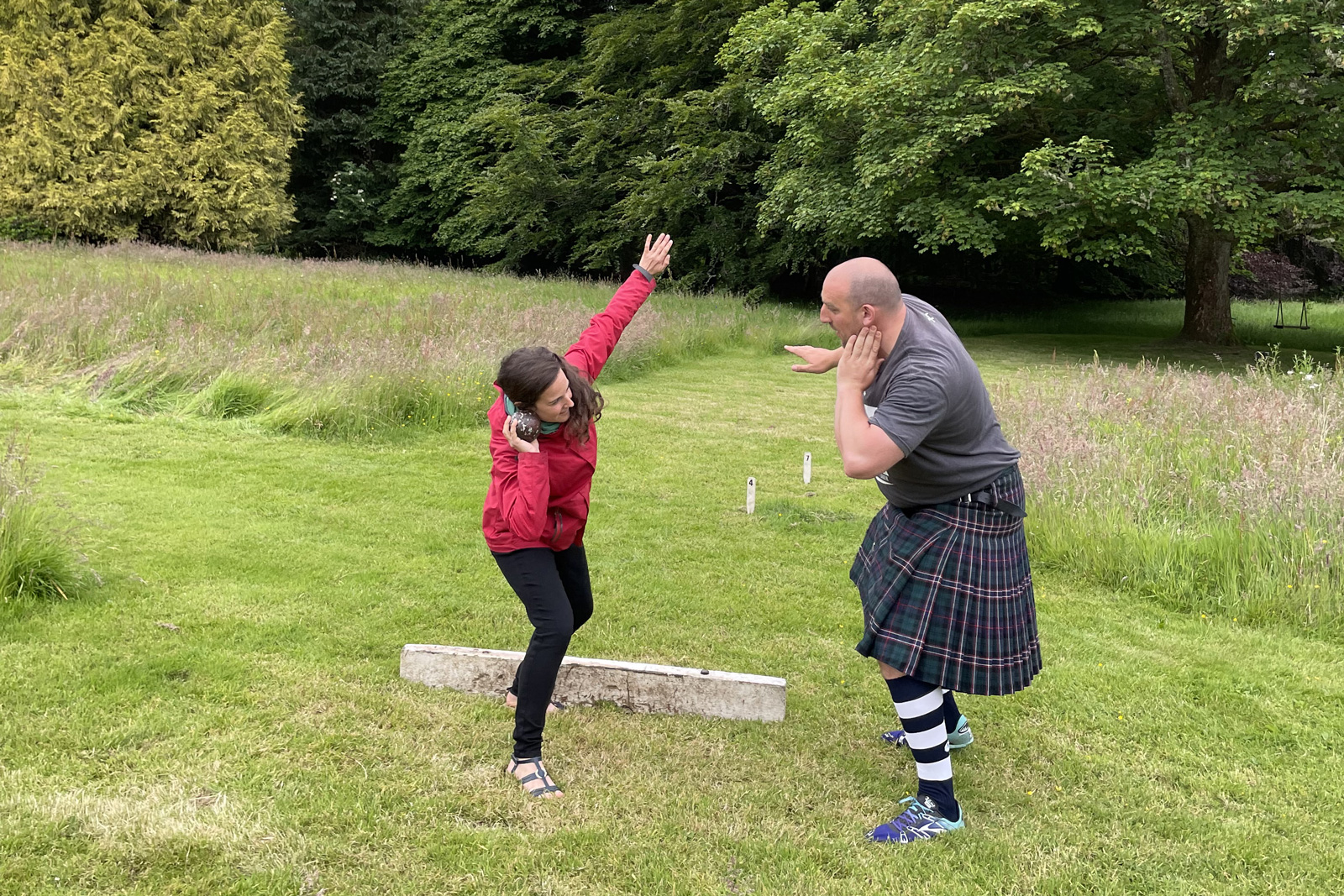 Man and woman posing to throw a steel ball in a large field