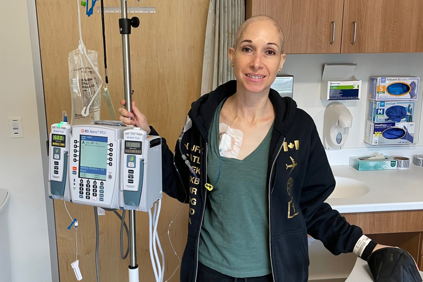 Woman standing next to an IV drip in a hospital room