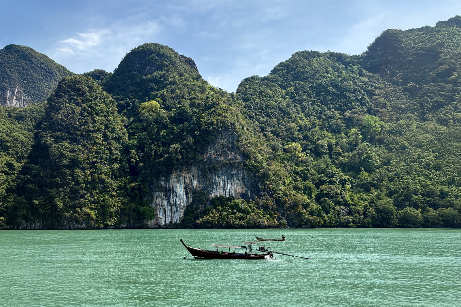 Boat floating in the middle of a lake, with large mountains in the background