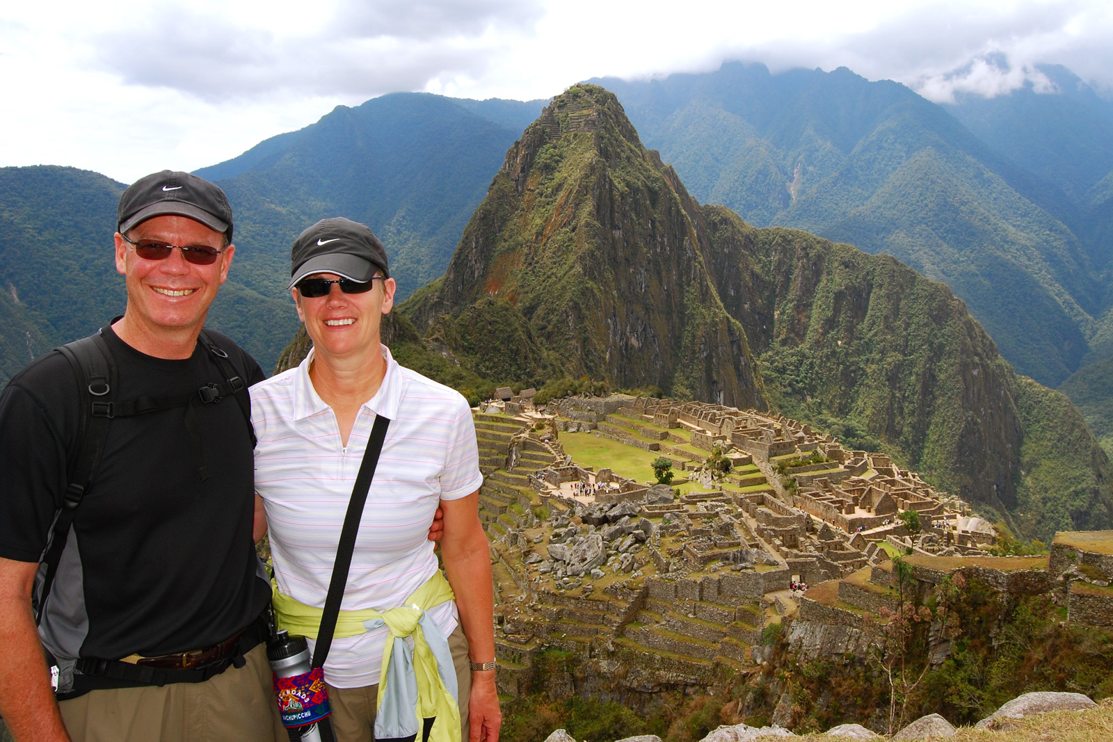 Man and woman smiling and hugging, with large ruins in the background
