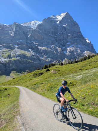 Backroads trip prep specialist riding down an alpine road with the mountains on the horizon.