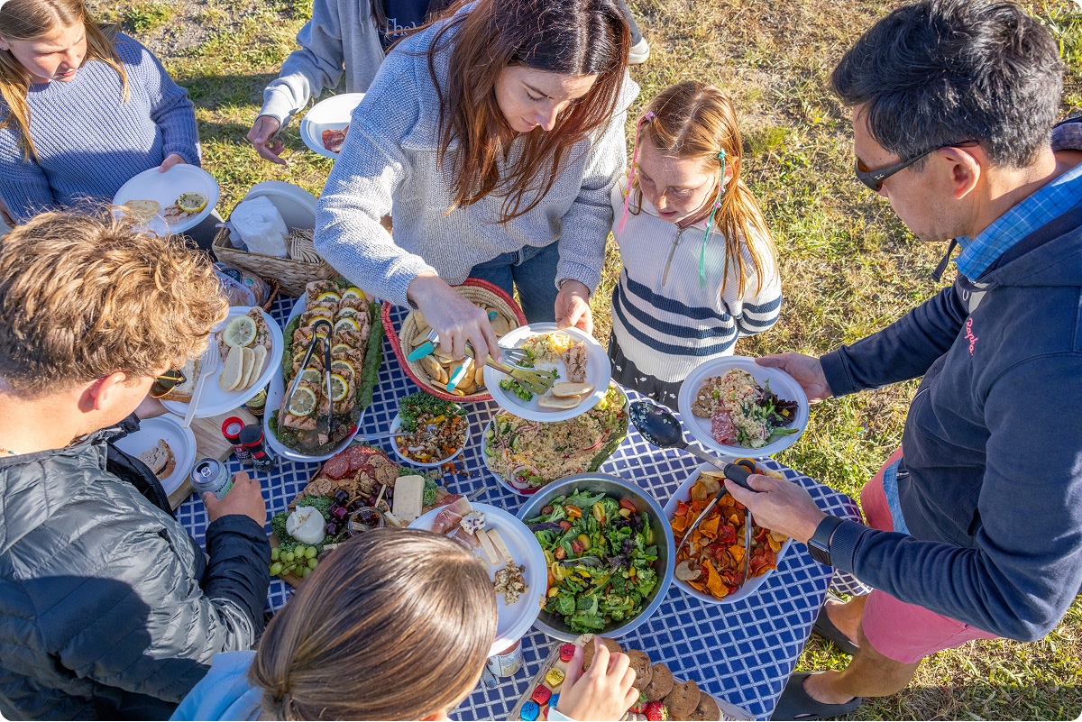 Group of people serving plates at a picnic table