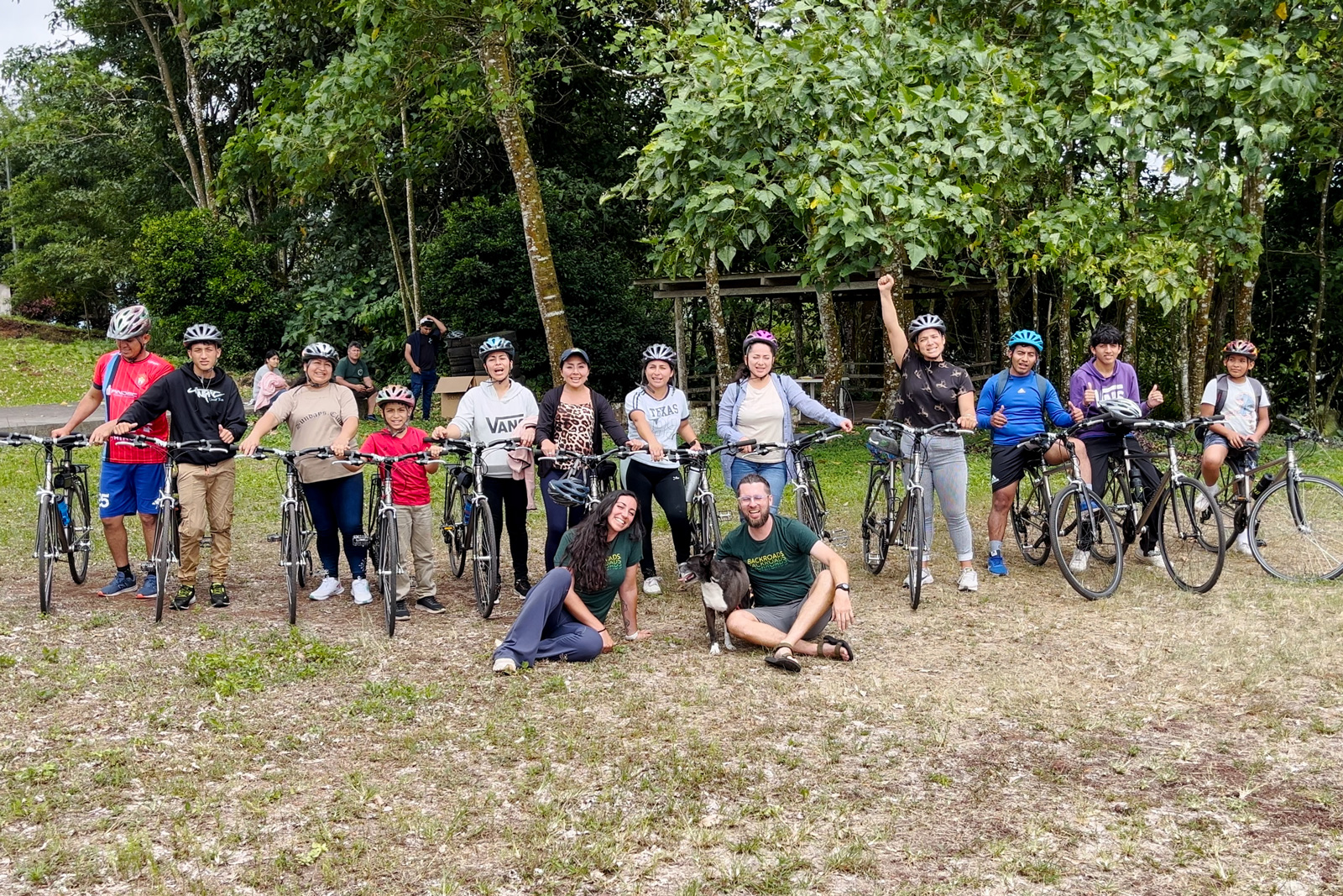 Group of people standing with bicycles and large trees in the background