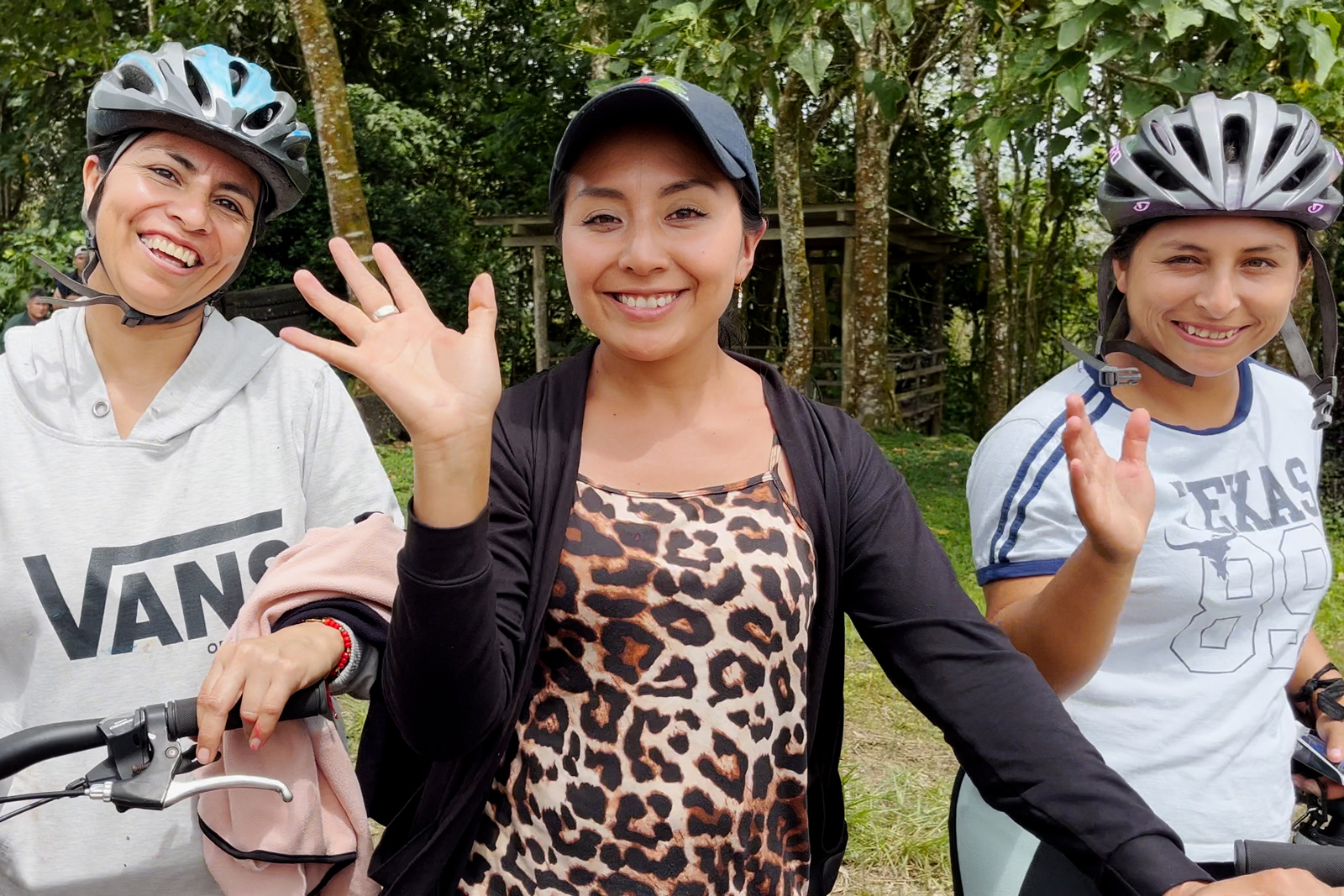 Three women smiling with large trees in the background