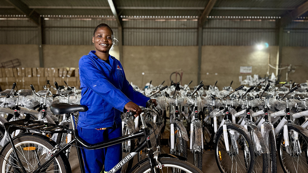 Women in a blue jacket holding a bicycle, in a warehouse full of bicycles