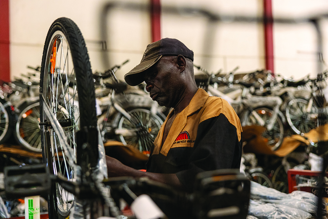 Man fixing a bike in a warehouse full of bicycles