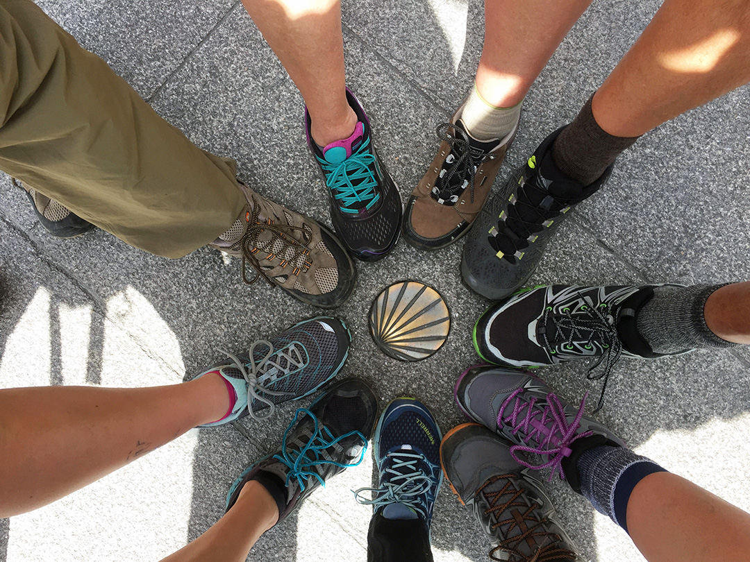 Hikers with their shoes in a circle, around a metal seashell on the floor
