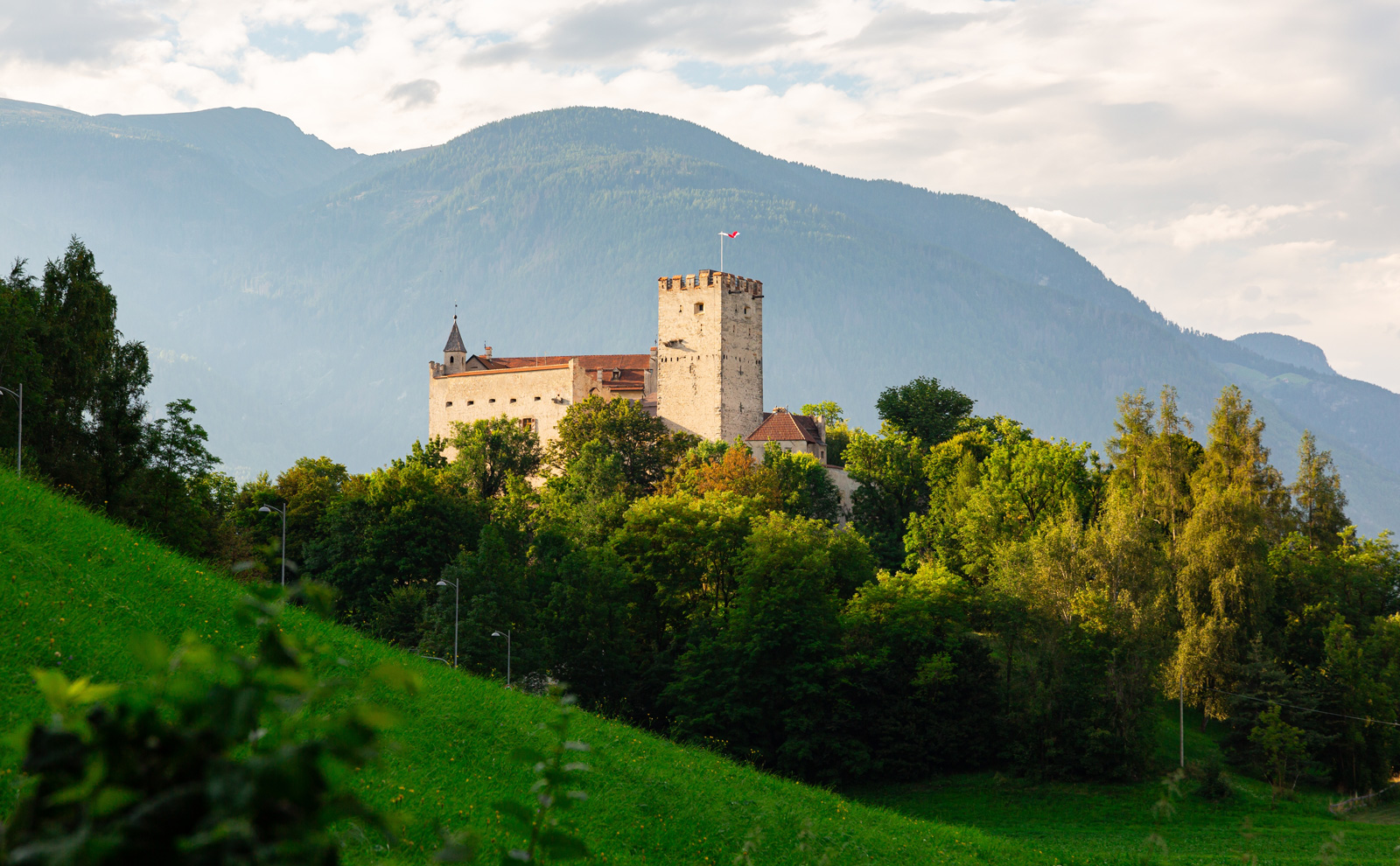 Castle-like building on top of a hill, with a grass valley in front