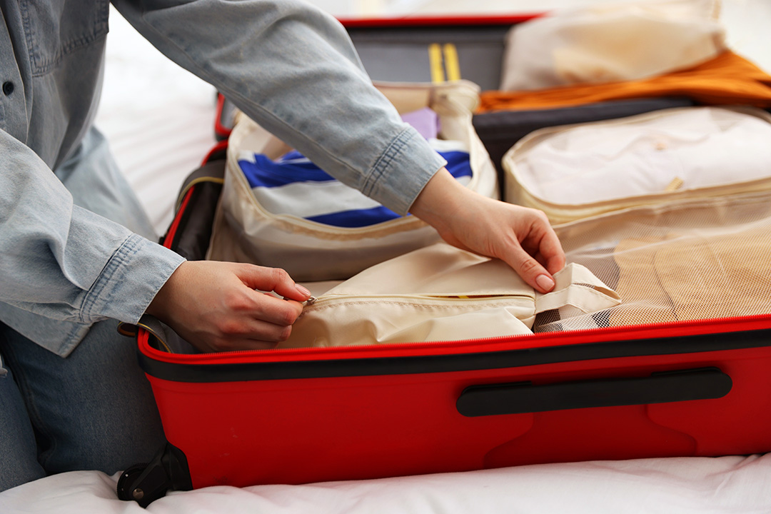 Person loading packing cubes into a red luggage