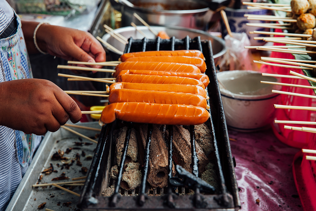 Man grilling sausages on a stick