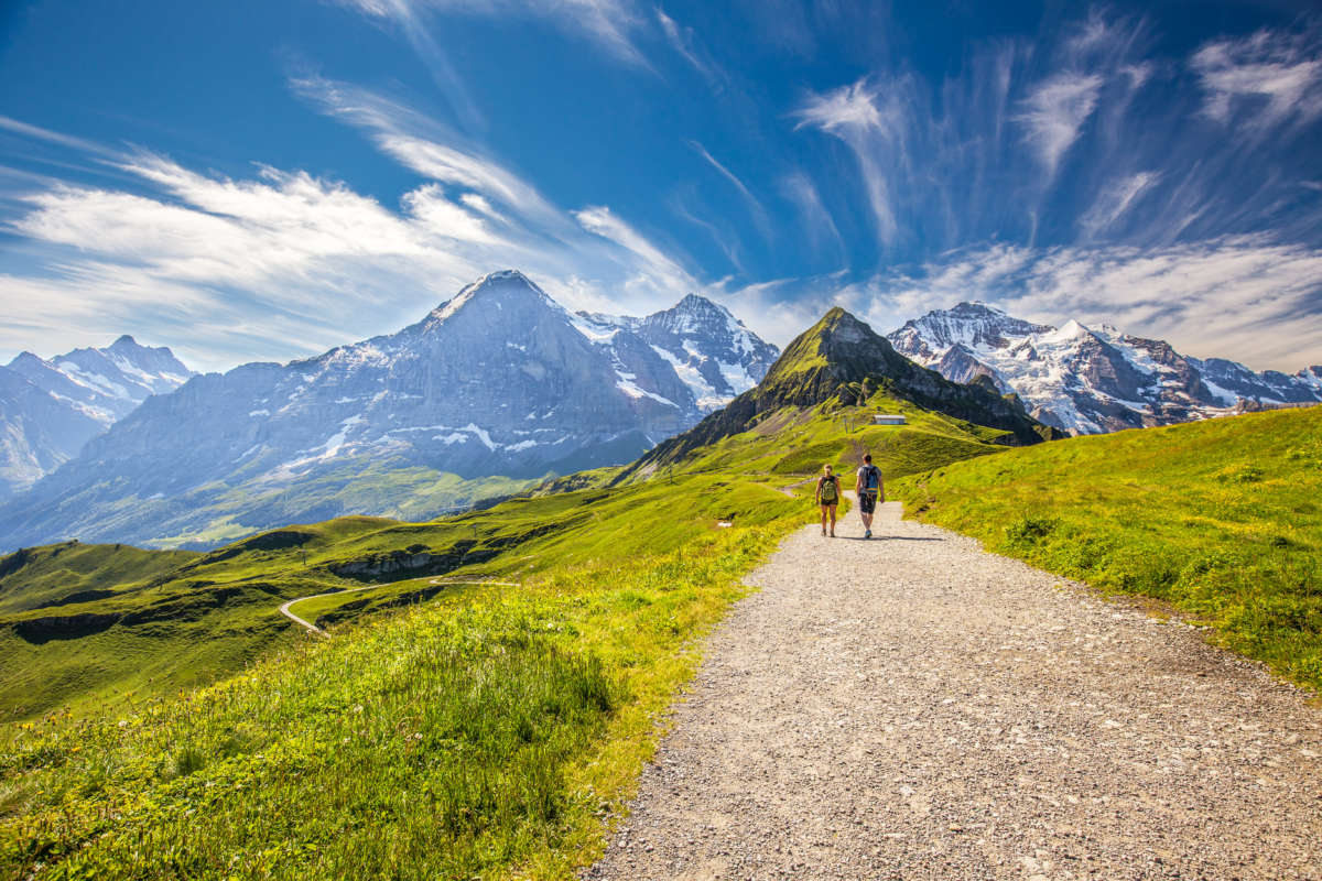 Hiking in panorama trail leading to Kleine Scheidegg from Mannlichen with Eiger, Monch and Jungfrau mountain (Swiss Alps) in the background, Berner Oberland, Grindelwald, Switzerland.