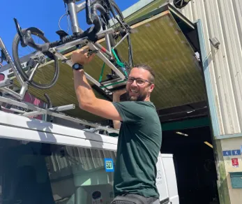 Image of a trip prep specialist loading bikes onto the top of a Backroads van