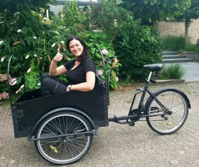 Image of a trip prep specialist in a bike basket. She is holding up a thumbs up.