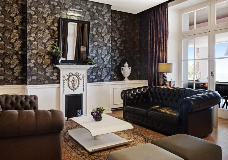 Indoor foyer, with black and brown leather couches, with a large window over a fireplace