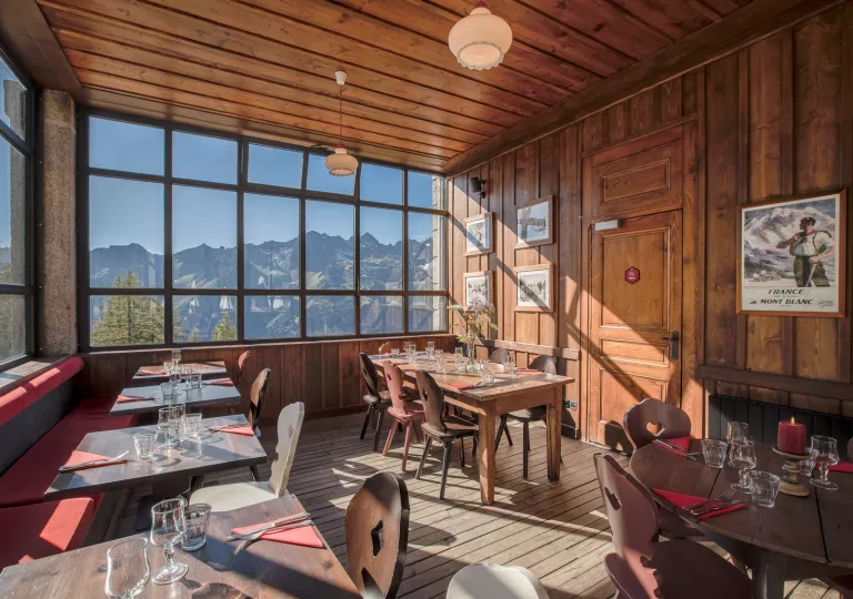 Dining area in a wooden-lodge room with large windows looking out to the mountains