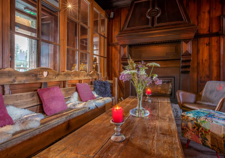 Indoor lodge with wooden furniture and leather seats, with a fireplace at the end of the room