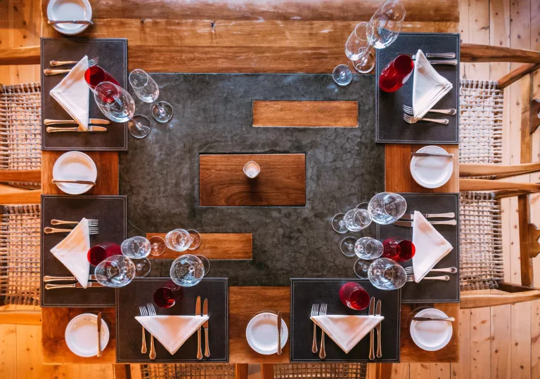 Top view of a dining table with silverware and wine glasses around the table