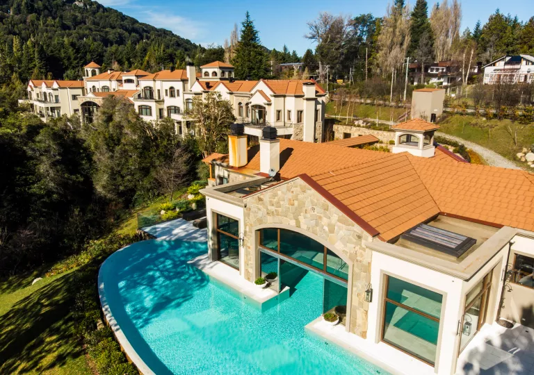 White and brown buildings with a pool surrounding one of the buildings