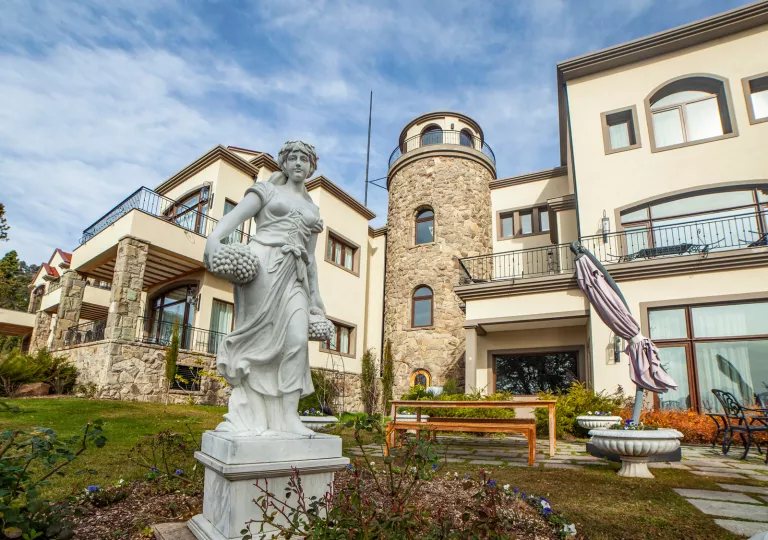 Exterior view of tan and stone building with a stone statue in the front