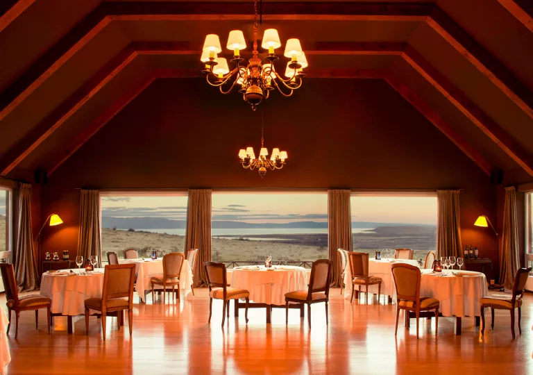 large dining room lit by chandeliers with windows overlooking ocean