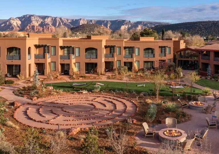 Exterior view of brown hotel building with a stone pathway in an outdoor garden