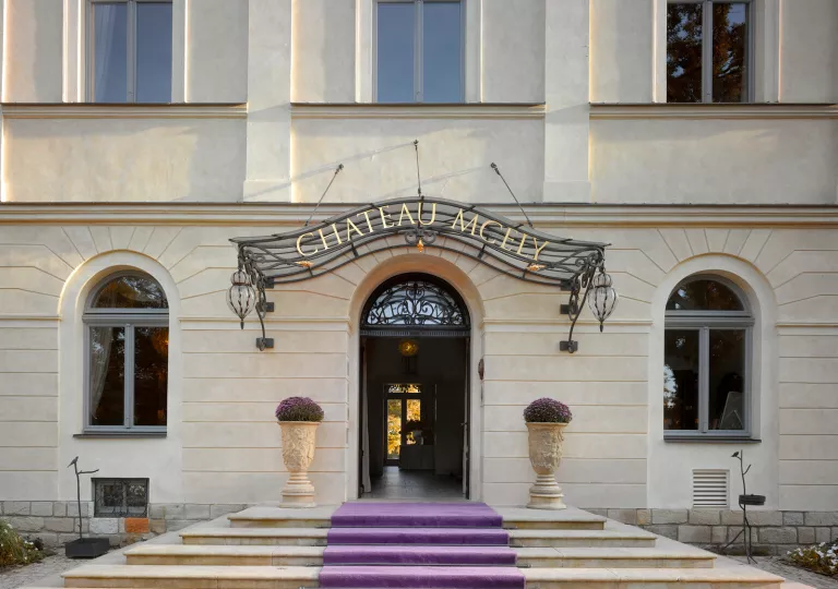Hotel entrance with stone stairs and a purple carpet leading to the doorway
