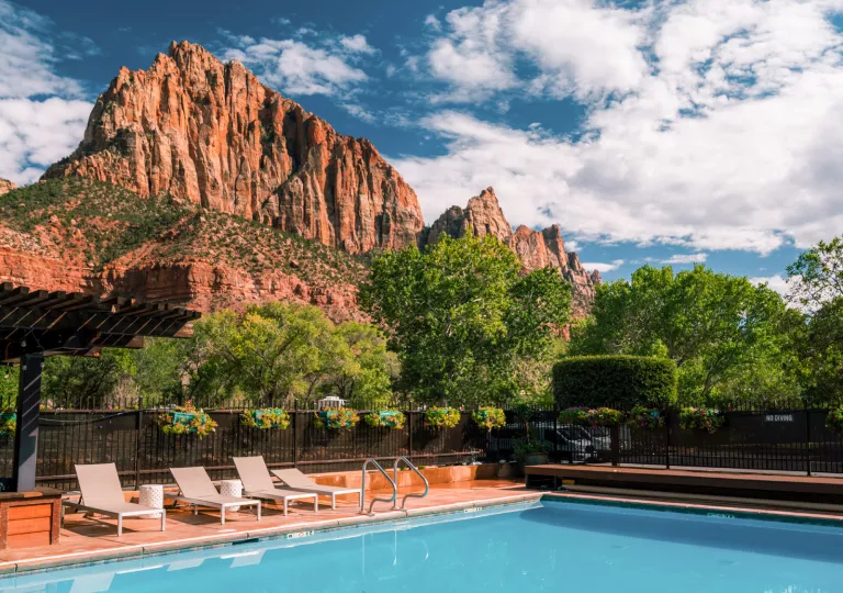pool with lounge chairs and mountains in background