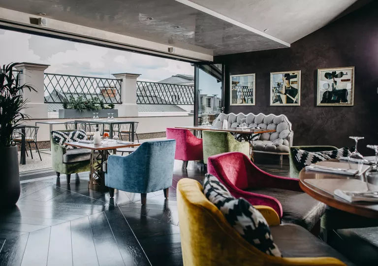 Indoor lounge with open doors leading do a stone balcony
