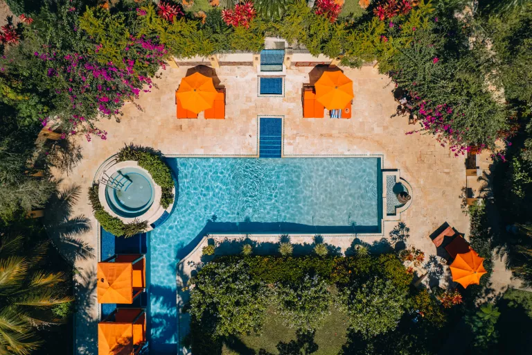 L shaped swimming pool surrounded by orange umbrellas