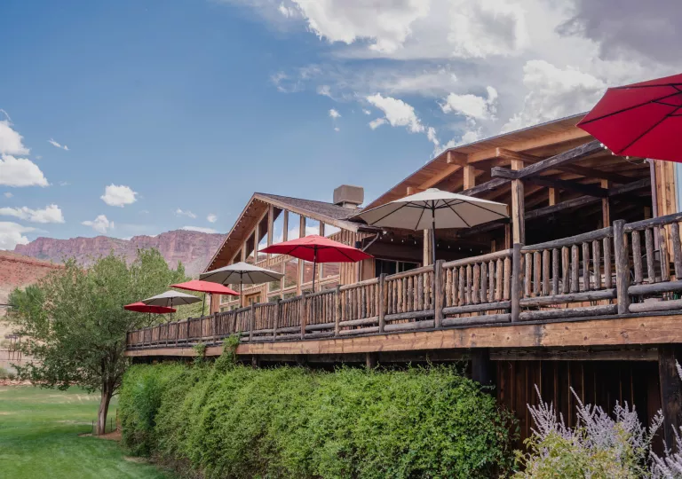 Elevated cabin-style building with wooden railings, in front of a grass valley