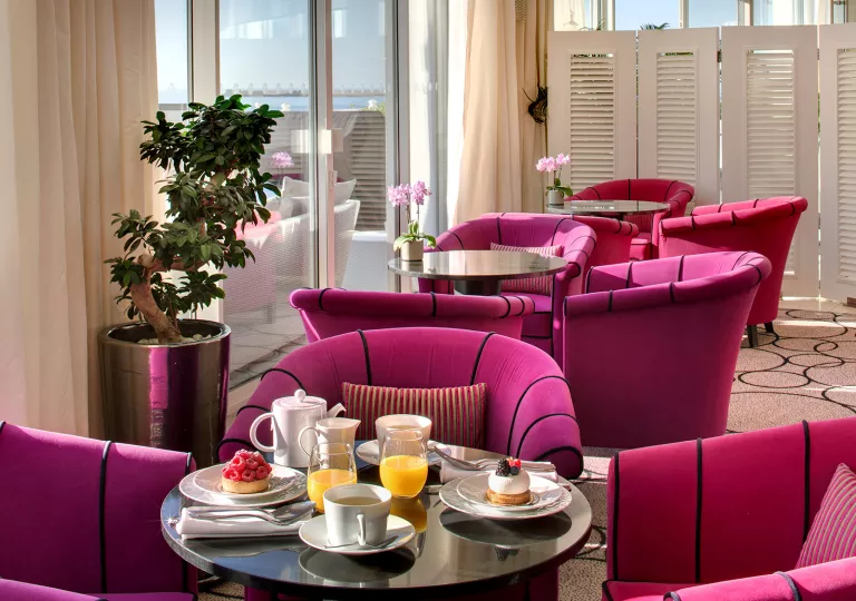 Indoor lounge with glass coffee tables and pink, cushioned chairs
