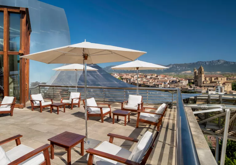 Outdoor rooftop patio with wooden chairs looking out to a small town