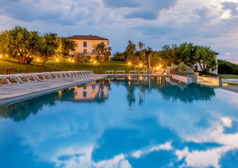 Outdoor pool with illuminated lights and large trees surrounding