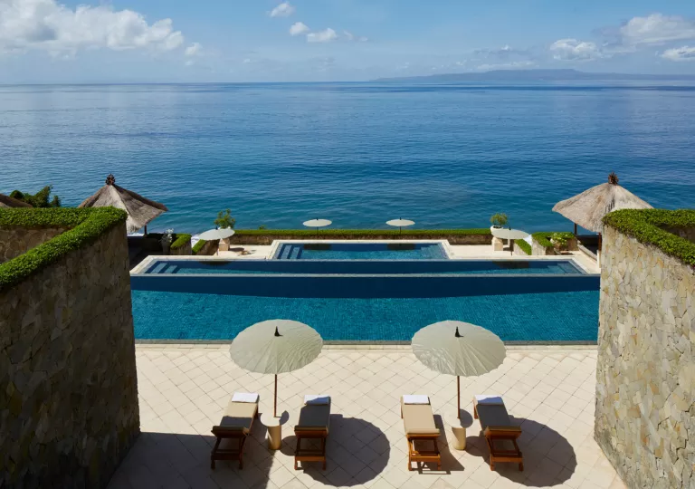 Lounge chairs by the pool looking out into the ocean