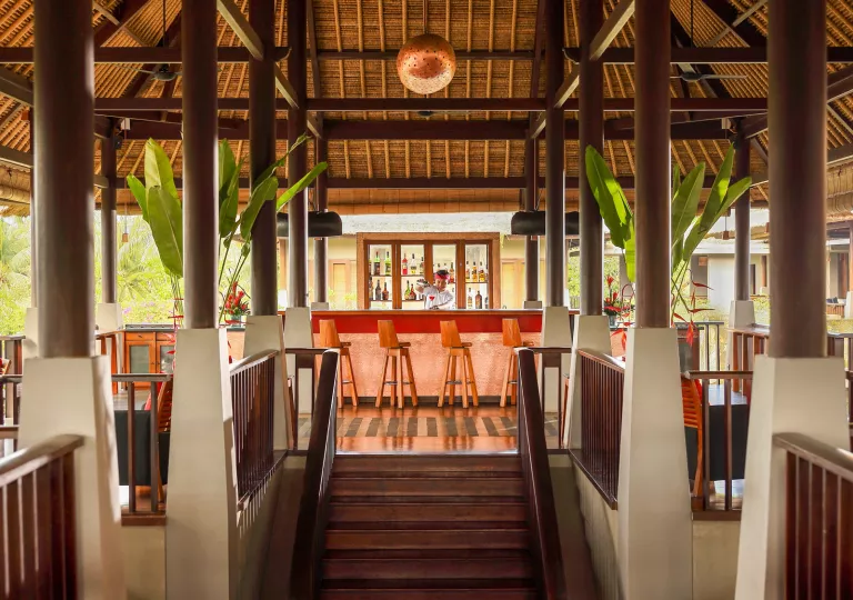 Indoor bar with a staircase in front and a bartender making drinks