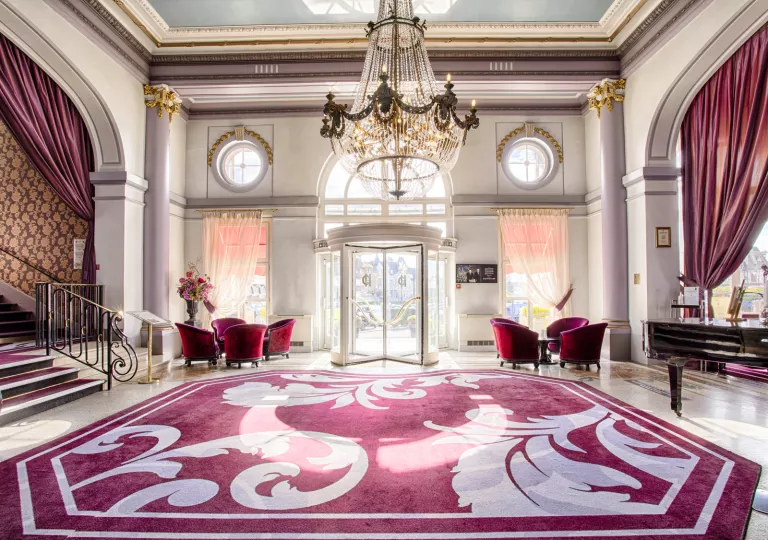 Hotel foyer with a red and white rug, and large chandelier