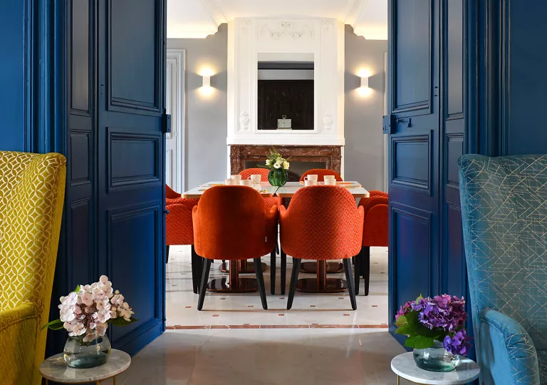 blue french doors open to red chairs around a table