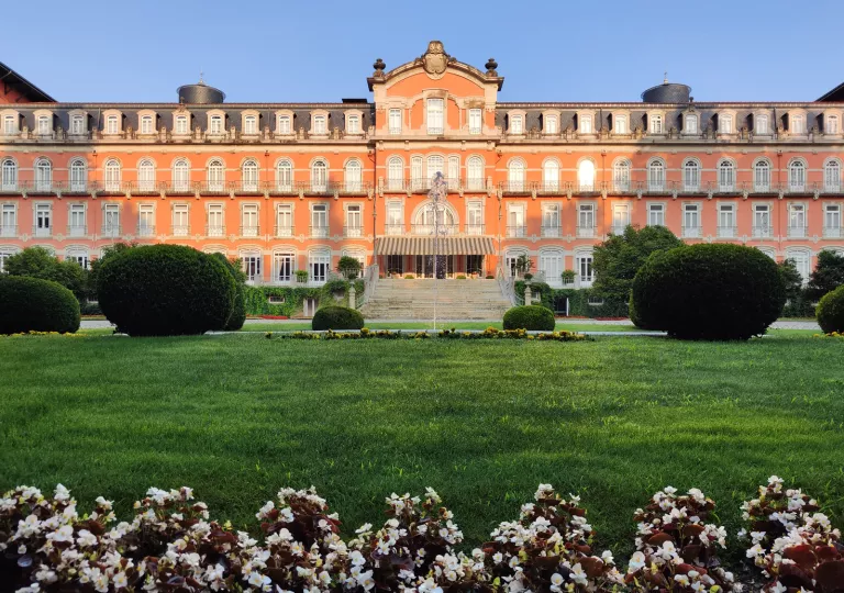 Exterior view of red building with a large staircase and a green grass field in front