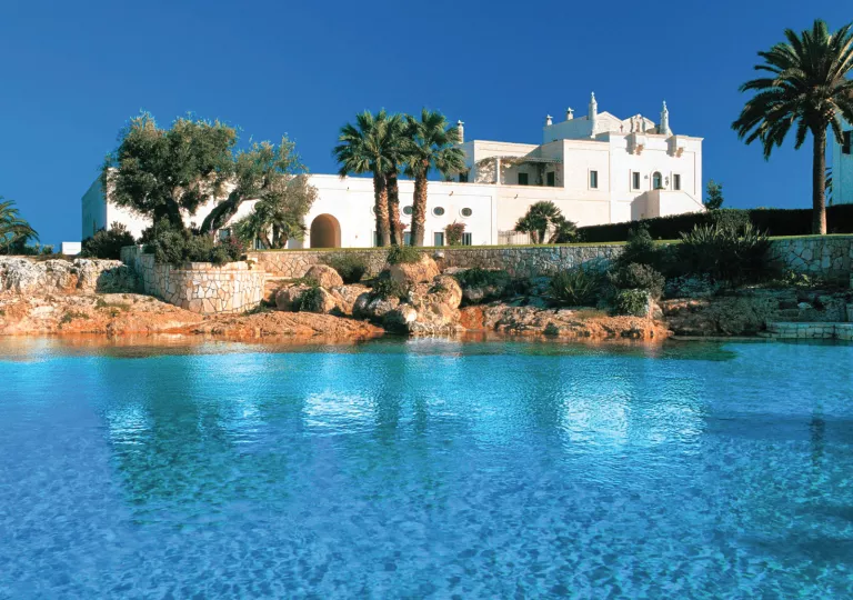 white building with palm trees next to ocean