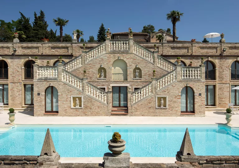 Exterior of stone building, with staircases on either side leading to an outdoor pool