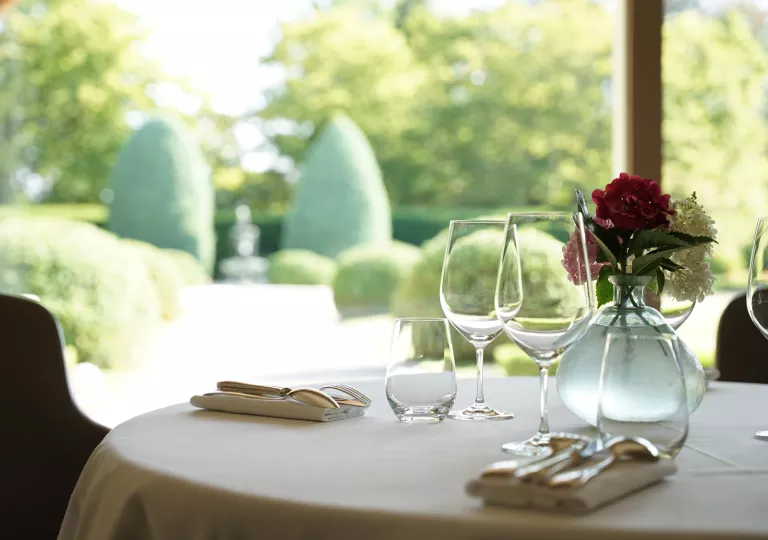 Dining table with a vase with flowers in the center, and 3 empty glasses of wine