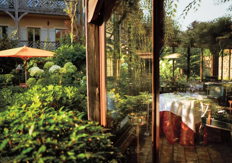 Indoor dining room with a large glass wall looking out to a garden