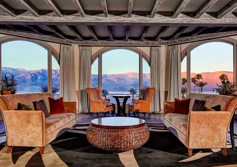 Indoor lounge and seating area, with tan velvet sofas and large windows