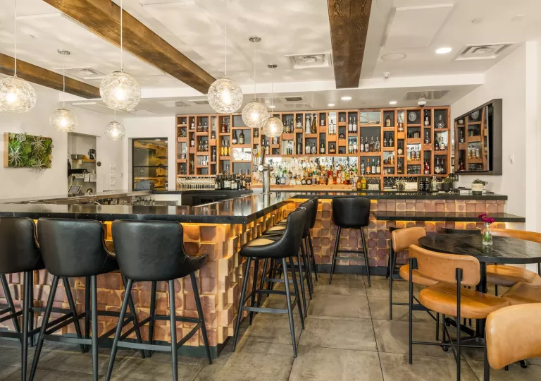 Indoor bar and lounge with black stools and cushioned, leather chairs