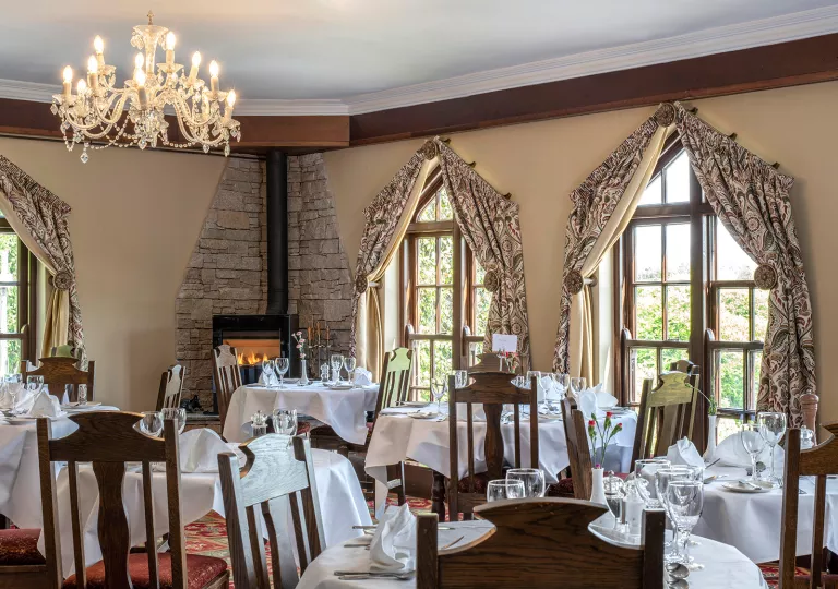 Indoor dining area with large, tan curtains over the windows and wooden chairs