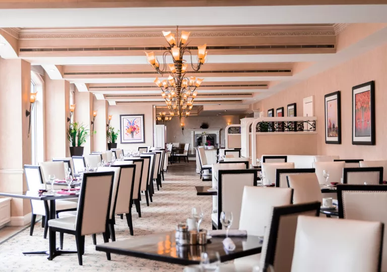 Indoor dining area with white and black cushioned chairs around square dining tables