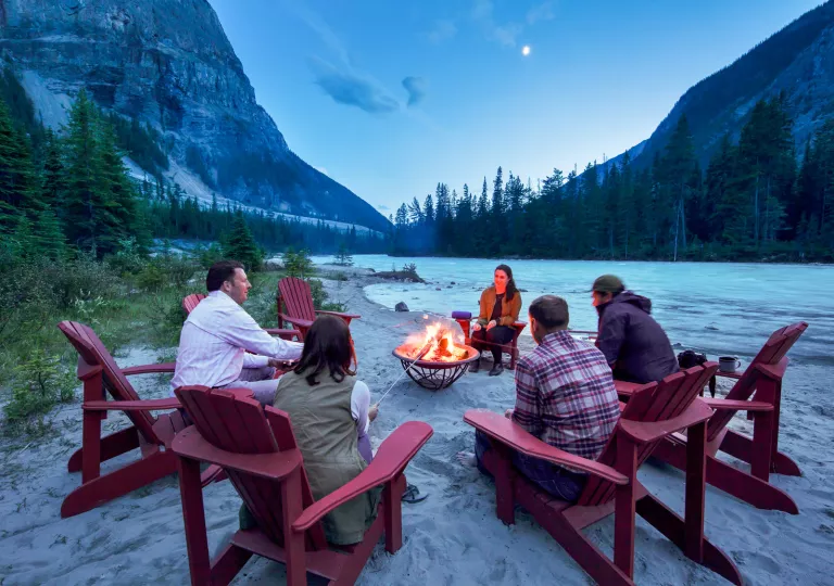 guests sitting in adirondack chairs circled around bonfire