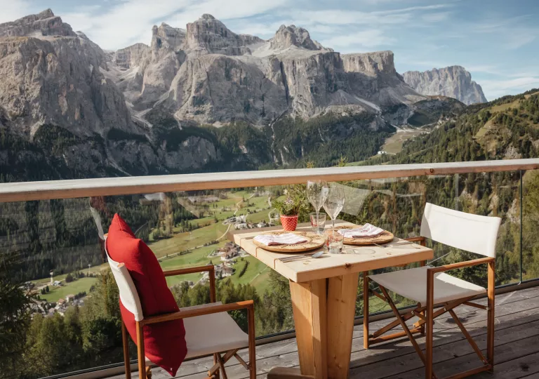 Two chairs with a dining table in the middle, looking out to large mountains