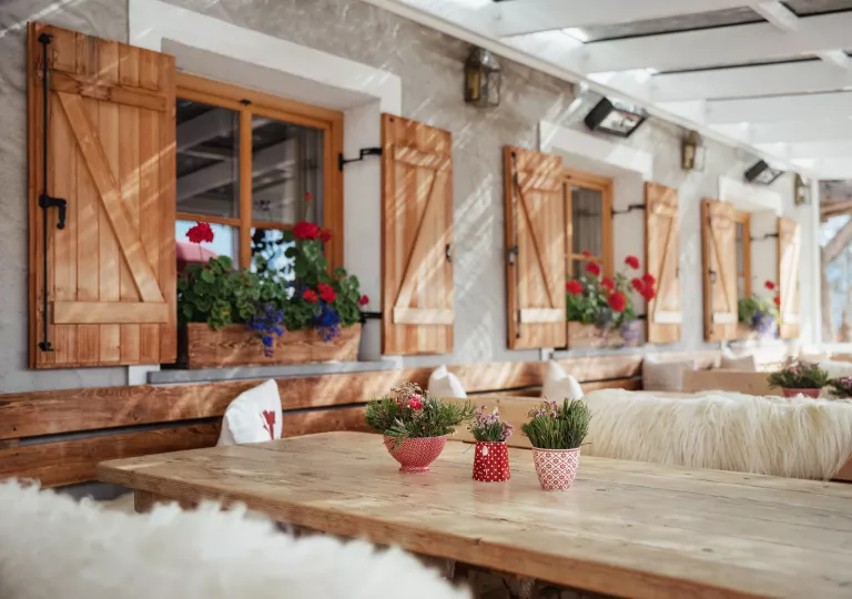 Rows of tables and benches with windowsills with flowers on the left