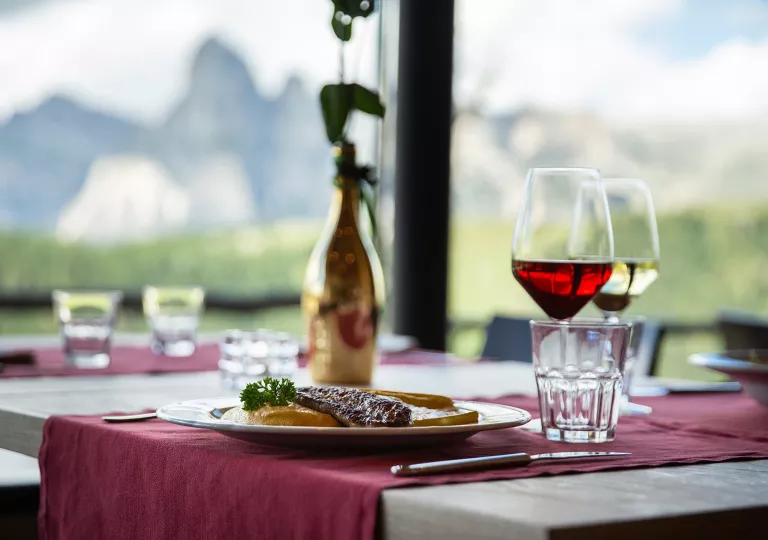 Dining table with a vase in the center and filled glasses of wine